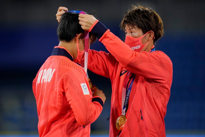 Japan team members adjust their gold medals at the medal ceremony for softball game at the 2020 Summer Olympics.