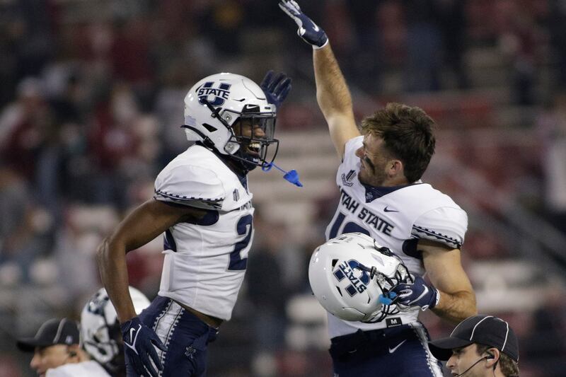 Utah State safety Dominic Tatum, left, and wide receiver Brandon Bowling celebrate the team’s 26-23 win against Washington State.