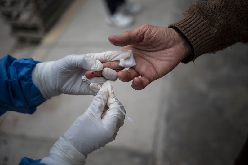In this June 30, 2020 file photo, a healthcare worker takes a blood sample during a house-to-house rapid antibody test drive in Villa el Salvador, on the outskirts of Lima, Peru. Antibody tests – which detect proteins created by the immune system in response to a virus – have numerous drawbacks. If taken too early, most people with the virus test negative.