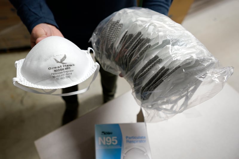 Ray Bellia holds up N95 personal protective masks, used by medical and law enforcement professionals, in the warehouse of his Body Armor Outlet store, Wednesday, Dec. 9, 2020, in Salem, N.H.