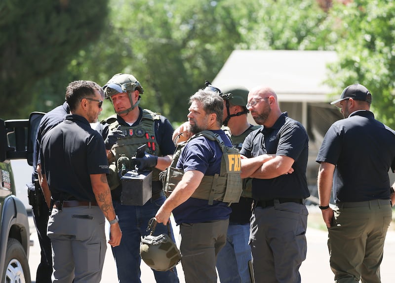 Law enforcement agents confer at the home of Craig D. Robertson who was shot and killed by FBI agents in Provo.