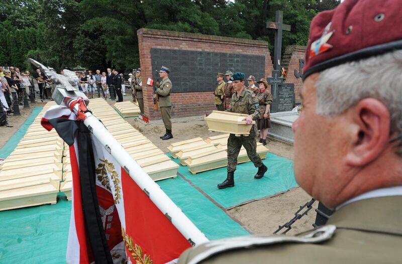 In this Aug. 24, 2012 photo, a soldier carries one of the coffins containing remains of World War II heroes during a ceremony ending archeological works at the Powazki cemetery in Warsaw, Poland. A Polish history institute is seeking to exhume and move th