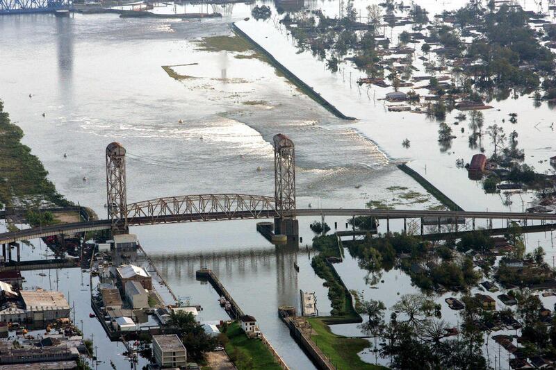 FILE - In this Aug. 30, 2005 file photo, floodwaters from Hurricane Katrina flow over a levee along Inner Harbor Navigaional Canal near downtown New Orleans.