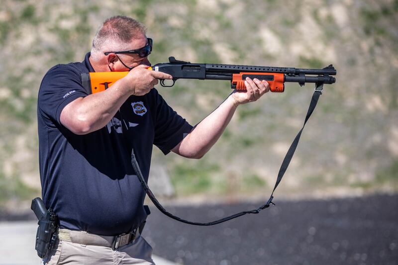 A police officer demonstrates a new less-lethal shotgun during a media event in Salt Lake City.