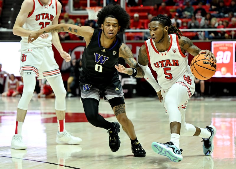 Washington Huskies guard Koren Johnson (0) defends Utah Utes guard Deivon Smith (5) at the Huntsman Center on Dec. 31, 2023.
