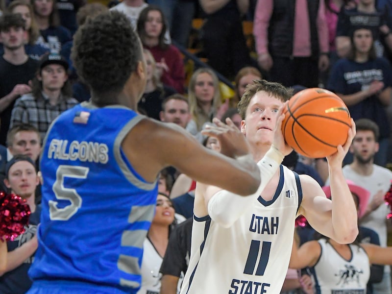 Utah State guard Max Shulga (wearing white) looks to shoot the ball as Air Force guard Ethan Taylor defends.