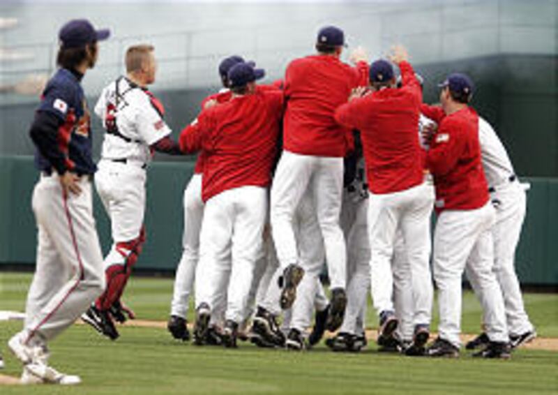 Team Japan closing pitcher Kyuji Fujikawa, left, watches as Team USA celebrates after Alex Rodriguez hit a game-winning single.