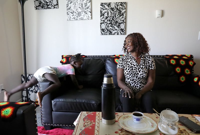 Siyanna Inna climbs on the couch as her mother, Tabitha Kwayge, a Sudanese refugee, laughs at their apartment in Midvale, Utah.