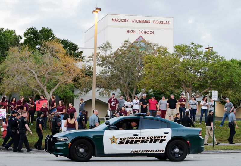In this Feb. 28, 2018 photo, a police car drives by Marjory Stoneman Douglas High School in Parkland, Fla., as students returned to class for the first time since a former student opened fire there with an assault weapon. The United States is in the midst
