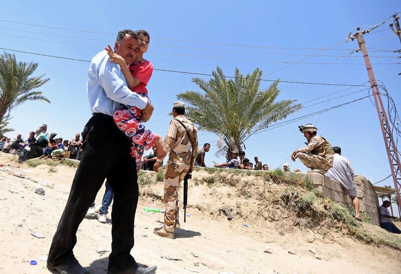 Iraqi security forces guard displaced Iraqis from Ramadi as they prepare to cross the Bzebiz bridge after spending the night walking towards Baghdad, as they flee their hometown, 65 km west of Baghdad, Iraq, Saturday, May 16, 2015. Islamic State militants