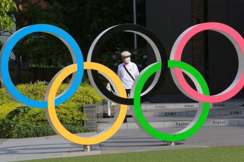A man walks past the Olympic rings in Tokyo in 2021.
