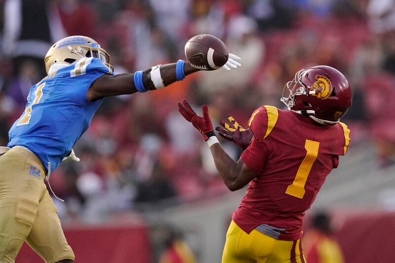 Southern California wide receiver Gary Bryant Jr., wearing red, catches a pass as UCLA defensive back Jay Shaw defends