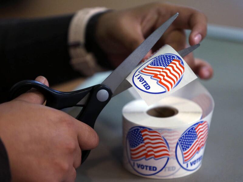 A volunteer hands out stickers to voters in Carson City, Nev., on Tuesday, Nov. 4, 2014.