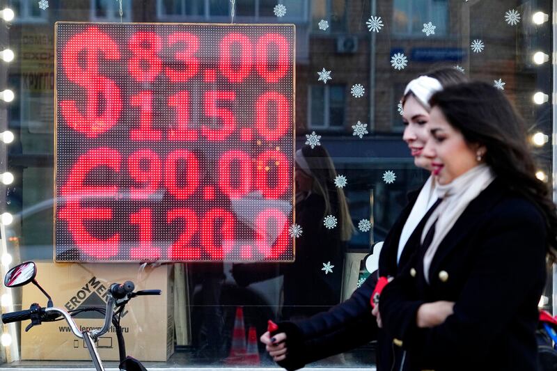 People walk past a currency exchange office screen displaying the exchange rates in downtown Moscow.