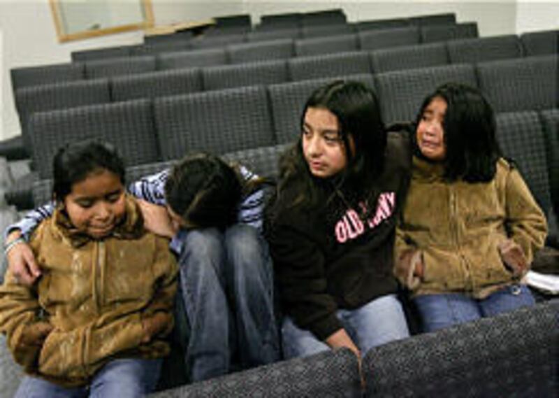 Four girls console each other after a meeting Wednesday in Hyrum. The mother of three of the girls was arrested in Tuesday's raid at the Swift and Co. plant.