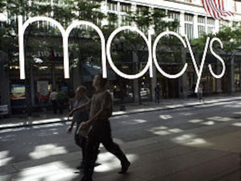 A Macy’s window reflects pedestrians in Boston. The retailer plans to open up 68 stores on Monday with added coronavirus precautions.