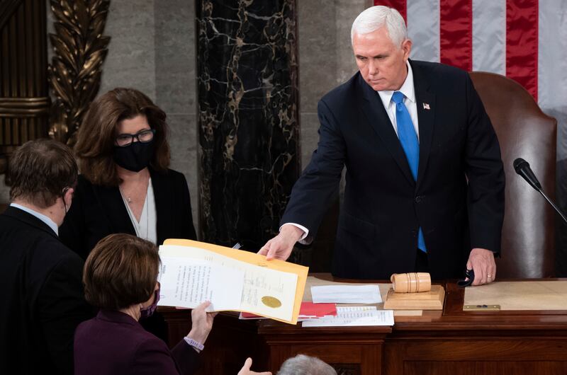 Vice President Mike Pence hands the electoral certificate from the state of Arizona to Sen. Amy Klobuchar, D-Minn., as he presides over a joint session of Congress as it convenes to count the Electoral College votes cast in November’s election, at the Capitol in Washington, Wednesday, Jan. 6, 2021.