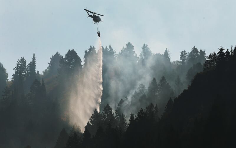 A helicopter drops water on the Pole Creek Fire in Woodland Hills on Friday, Sept. 21, 2018.