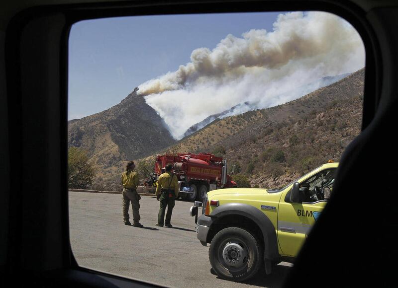 Seen through a window, firefighters watch for spot fires from Montezuma Pass Overlook near Sierra Vista, Ariz. on Sunday, June 19, 2011. Winds gusting to 50 mph hampered efforts to control the Monument Fire grounding all attacks from the air.