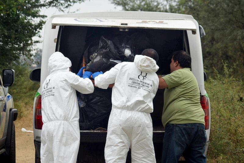 In this Nov. 15, 2013 file photo, forensic investigators put a body that was recovered from a mass grave into a vehicle in La Barca, Mexico. The number of bodies found in almost two dozen clandestine graves in western Mexico, near the border between Jalis