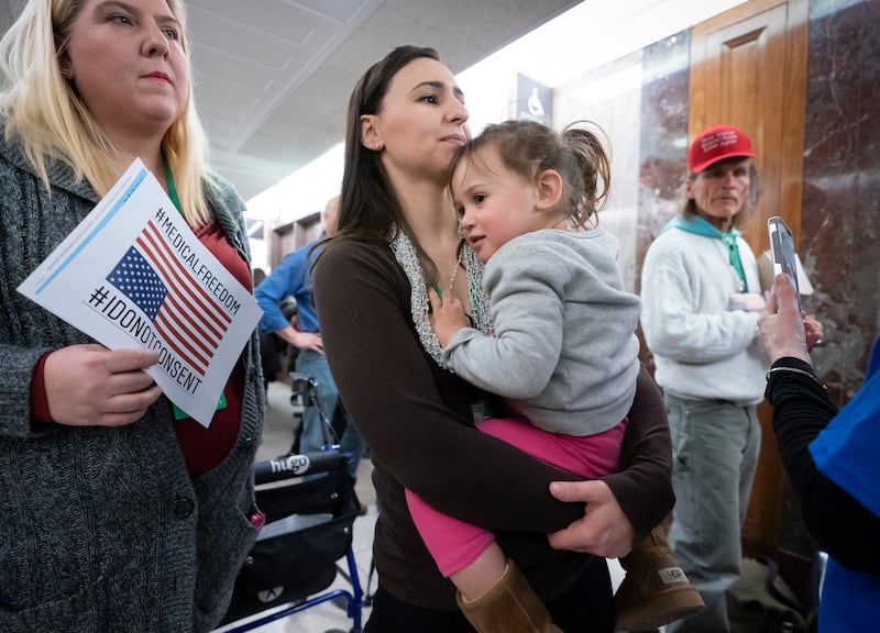 Sarah Myriam of New Jersey holds her daughter Aliyah, 2, as they join activists opposed to vaccinations outside a Senate Health, Education, Labor and Pensions Committee hearing on the safety of vaccines, on Capitol Hill in Washington, Tuesday, March 5, 20