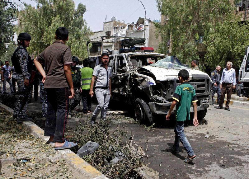 Iraqis gather at the scene of a bomb attack in the commercial area of Karradah in Baghdad, Iraq, Thursday, May 30, 2013. A series of morning bomb explosions in Baghdad and the northern Iraqi city of Mosul on Thursday, killed and wounded dozens of people,