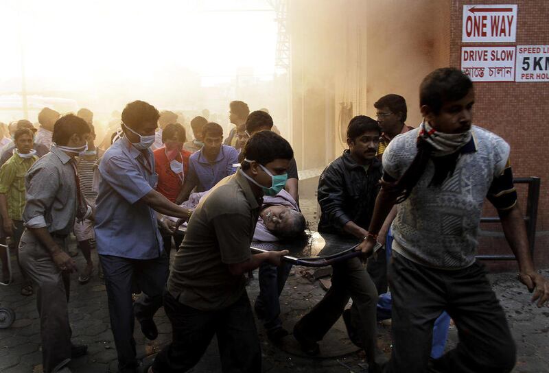 People evacuate patients after a fire broke out at a nursing home in Kolkata, India, Friday, Dec. 9, 2011. The fire swept through a multistory nursing home in eastern India early Friday, trapping many elderly residents in the smoke-filled building, an off