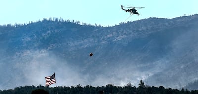 A helicopter retrieves a bucket of water while fighting the Coal Hollow Fire in Spanish Fork Canyon on Thursday, Aug. 16, 2018.