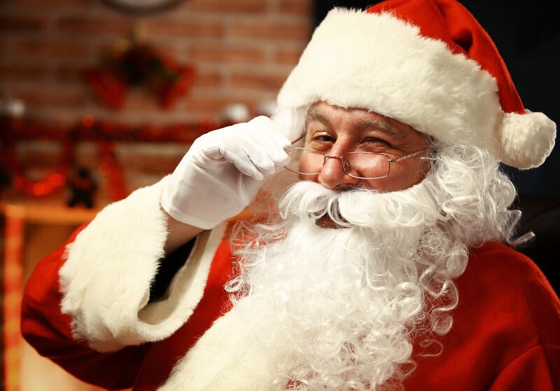 Portrait of happy Santa Claus holding Christmas letter in his hands and looking at camera