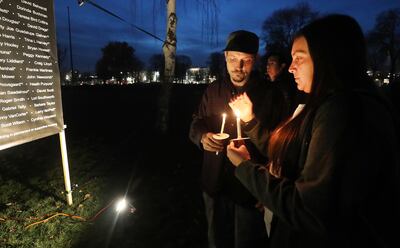 Alyssa Sallee and Jeremiah Giles hold candles near a list of 121 homeless men and women who died during the year during a candlelight vigil in Salt Lake City on Thursday, Dec. 20, 2018, at Pioneer Park.