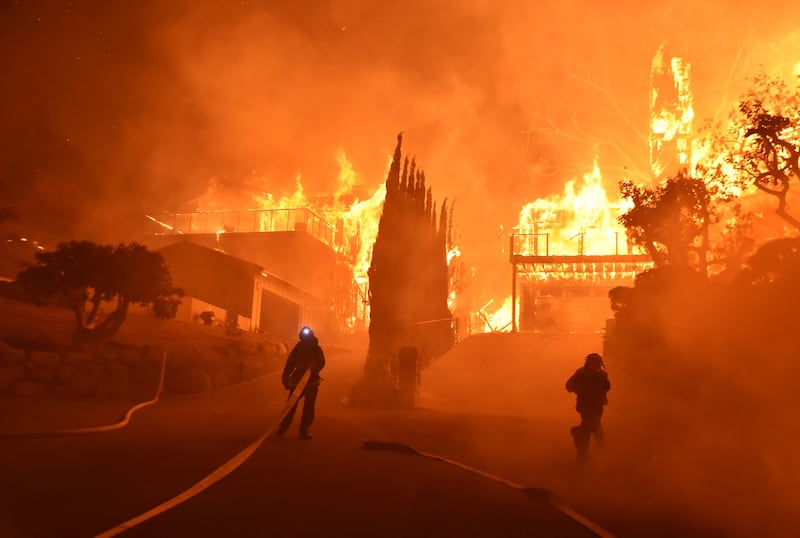 In this photo provided by the Ventura County Fire Department, firefighters work to put out a blaze burning homes early Tuesday, Dec. 5, 2017, in Ventura, Calif. Authorities said the blaze broke out Monday and grew wildly in the hours that followed, consum