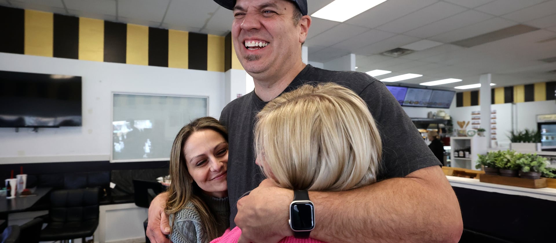 Clint Atwater hugs Catrina Nelson and April Sintz, as he gets ready to leave Avenue Bakery in American Fork.