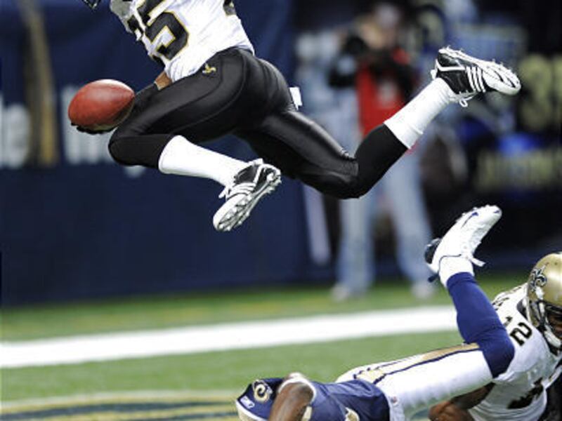 New Orleans Saints running back Reggie Bush, top, leaps over St. Louis Rams safety Oshiomogho Atogwe for a three-yard touchdown during the second quarter of an NFL football game Sunday in St. Louis.