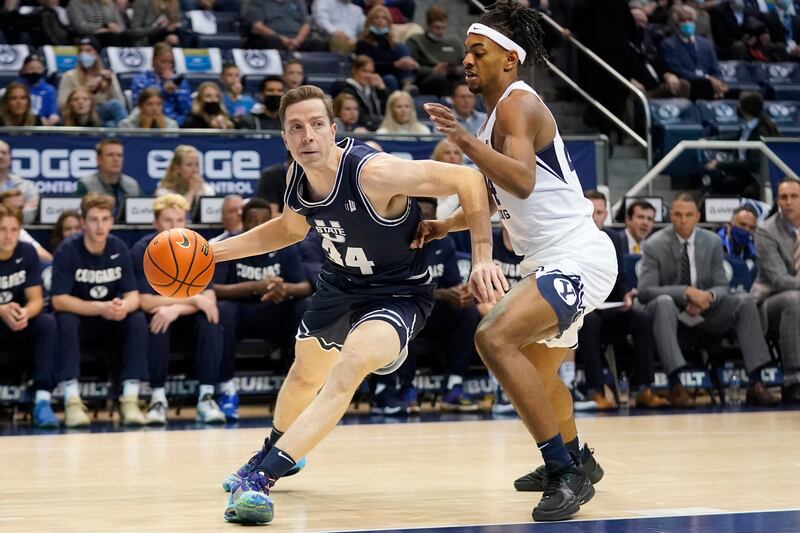 Utah State forward Justin Bean, wearing blue, drives as BYU forward Seneca Knight defends