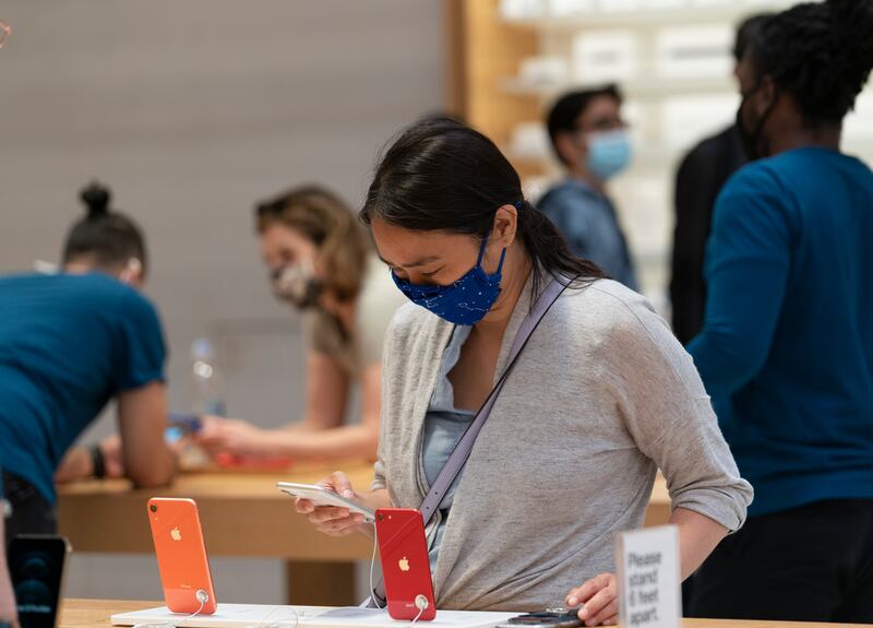 A customer looks at the iPhone 12 in an Apple store on Friday, May 21, 2021, in New York.