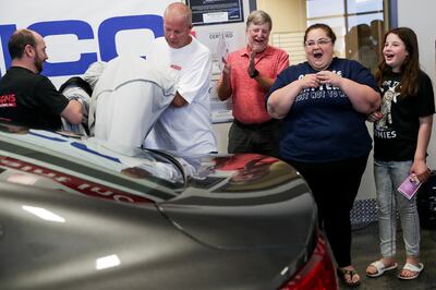 Darlene Lefevre and her daughter, Sophia, 10, watch as the cover is pulled off a 2015 Chrysler 200 that was donated to them at Higgins Body and Paint in West Valley City on Wednesday, June 27, 2018. Geico and Higgins Body and Paint, along with other orga