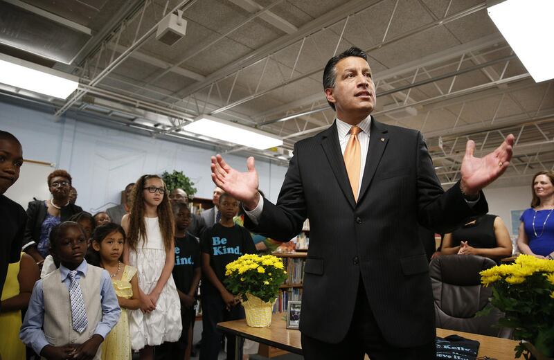 Nevada Governor Brian Sandoval, right, holds a bill signing ceremony Wednesday, June 3, 2015, in Las Vegas. The ceremony was for Senate Bill 432, which allocates millions of dollars for for low performing schools in the 20 poorest zip codes in Nevada. (AP