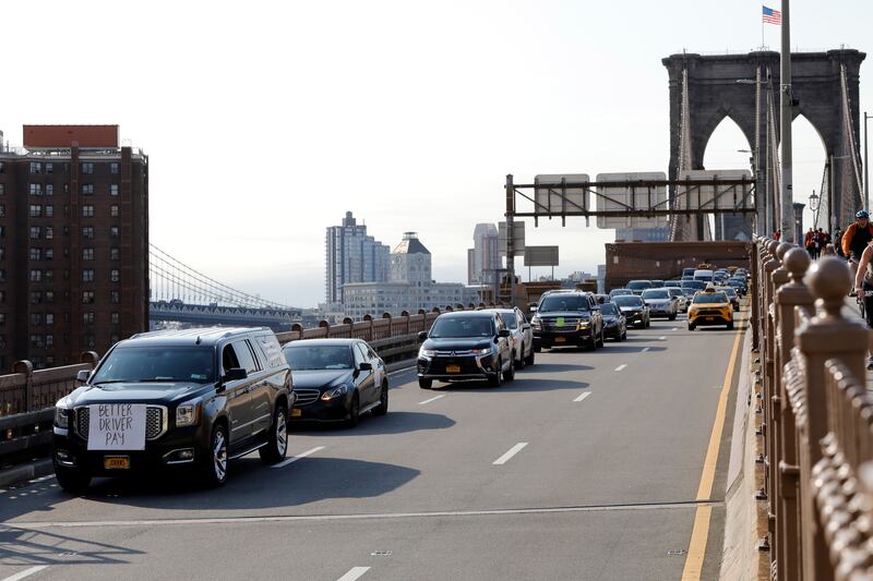 Uber and Lyft drivers, with signs on their vehicles supporting better wages, cross the Brooklyn Bridge in a caravan of about 25 vehicles, Wednesday, May 8, 2019 in New York. The protests arrive just ahead of Uber's initial public stock offering, which is