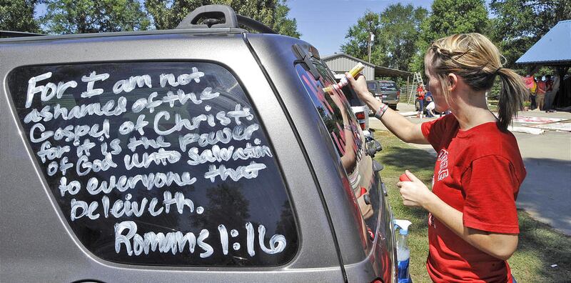 Kountze High School cheerleader Brooke Coates paints scripture verses on a car Wednesday, Sept. 19, 2012 in Kountze, Texas. The small Hardin County community is rallying behind the high school's cheerleaders after the squad members were told they could n