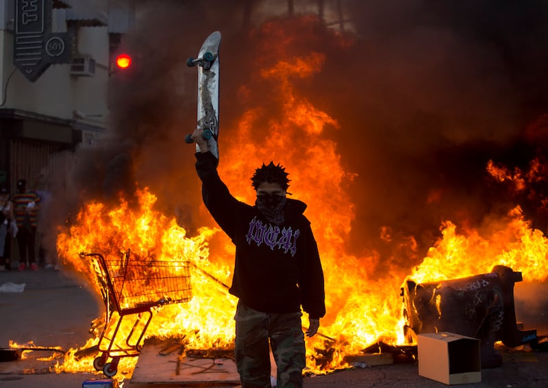 A protester holds a skateboard in front of a fire in Los Angeles, Saturday, May 30, 2020, during a protest over the death of George Floyd, a handcuffed black man who died in Minneapolis police custody on May 25. (AP Photo/Ringo H.W. Chiu)