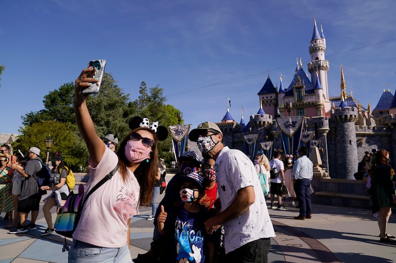 A family takes a photo in front of Sleeping Beauty’s Castle at Disneyland in Anaheim, Calif.