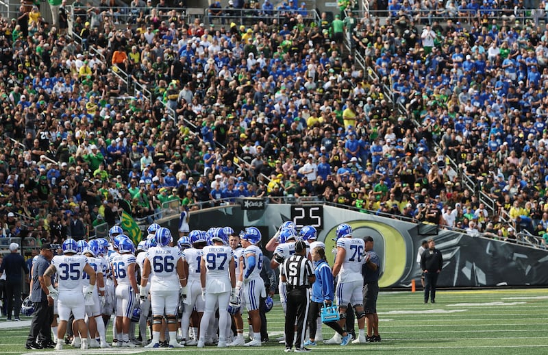 Oregon and BYU fans watch as Cougar players huddle during a timeout of game at Autzen Stadium in Eugene, Ore.