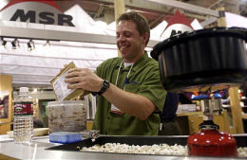 As a pot of water boils on a backpacking stove, Stephen Christie of Mountain Safety Research prepares a black bean dip at the Outdoor Retailer Winter Market trade show in 2001.
