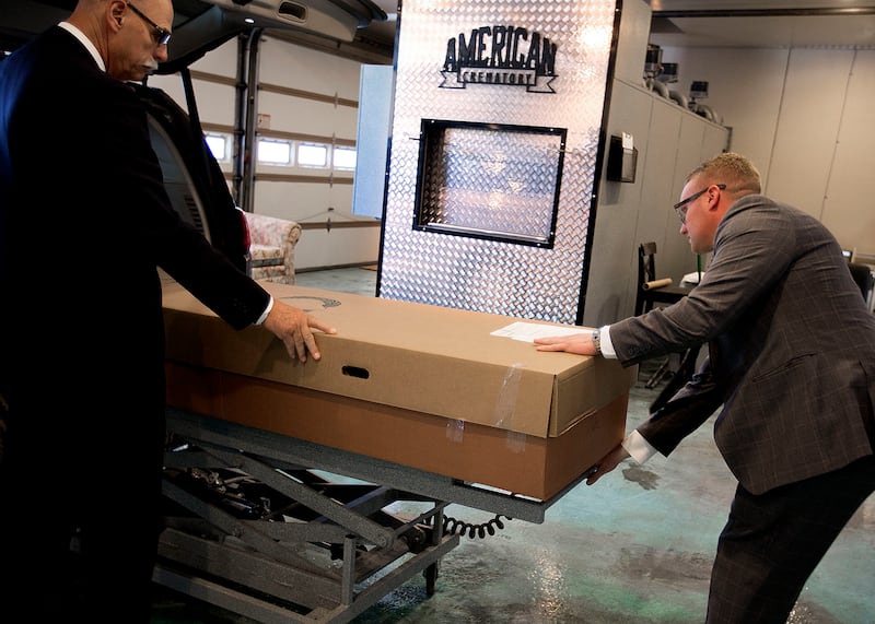 Boomer Benson, left, and Cole Houghton, owner of Tate Mortuary, prepare to cremate a body at the mortuary in Tooele in June 2018. Houghton has ordered an alkaline hydrolysis machine, making him the only mortician in Utah who will have the ability to offer