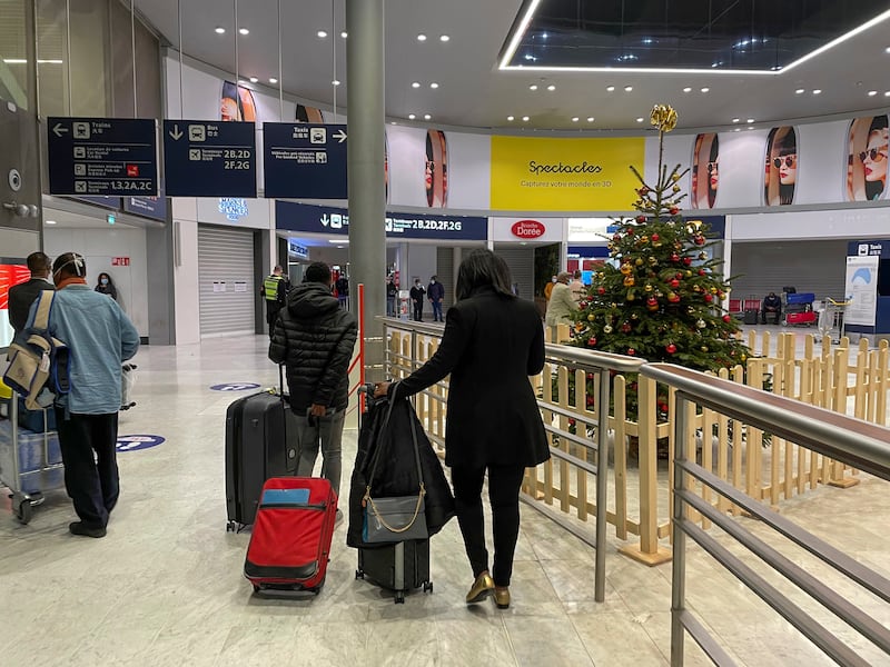Arriving passengers walk by a Christmas tree at Paris Charles de Gaulle airport terminal E Tuesday Dec. 22, 2020.