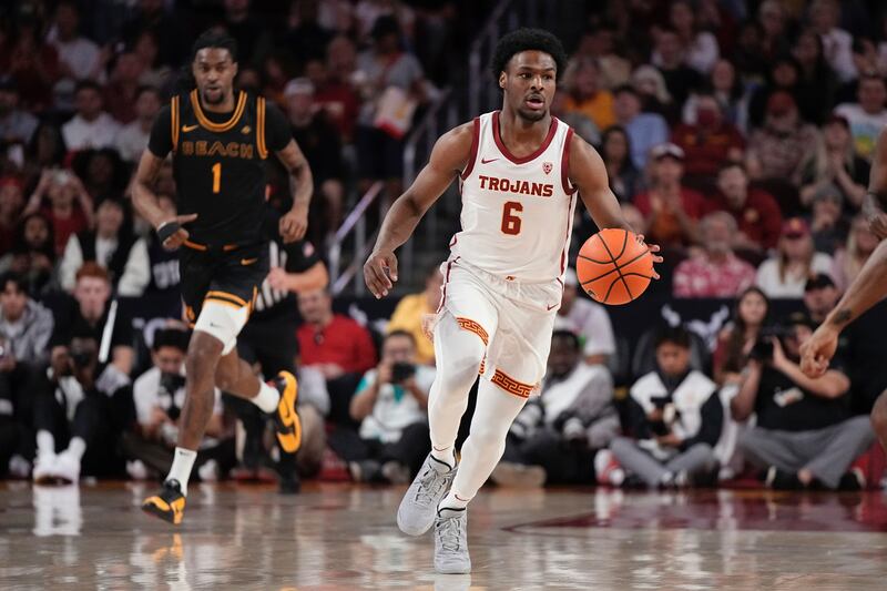 Southern California guard Bronny James, right, dribbles as Long Beach State forward Amari Stroud follows during the first half of an NCAA college basketball game Sunday, Dec. 10, 2023, in Los Angeles.