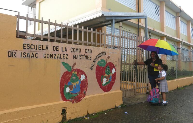 Ana Sanchez and her 8-year-old daughter Naiyari lock the gates of her school, The Dr. Isaac Gonzalez Martinez school, as part of their daily responsibilities in San Juan, Puerto Rico on Friday, May 5, 2017. The school is one of many closing this month ami