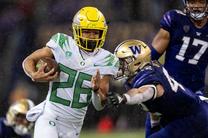 Oregon running back Travis Dye, wearing white, runs the ball
