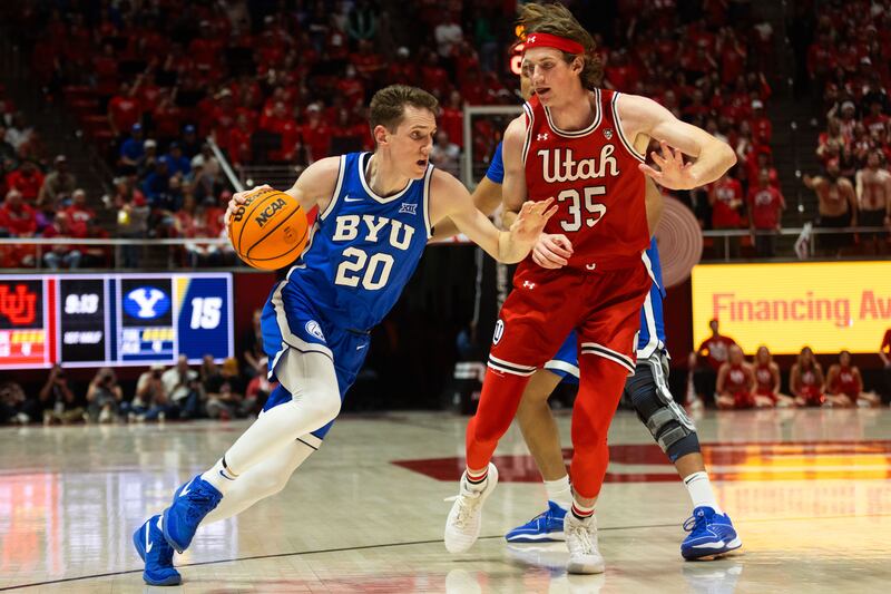 Brigham Young Cougars guard Spencer Johnson (20) drives the ball with Utah Utes center Branden Carlson (35) on defense during a men’s basketball game at the Jon M. Huntsman Center in Salt Lake City on Saturday, Dec. 9, 2023.