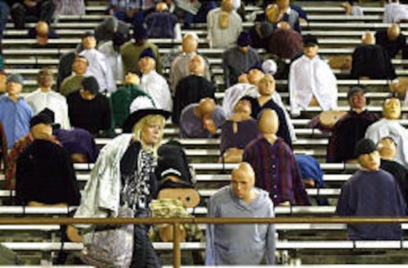 Odessa resident and movie extra Robin Bingham walks in front of dummy-filled stands during filming of "Friday Night Lights" in Odessa, Texas.